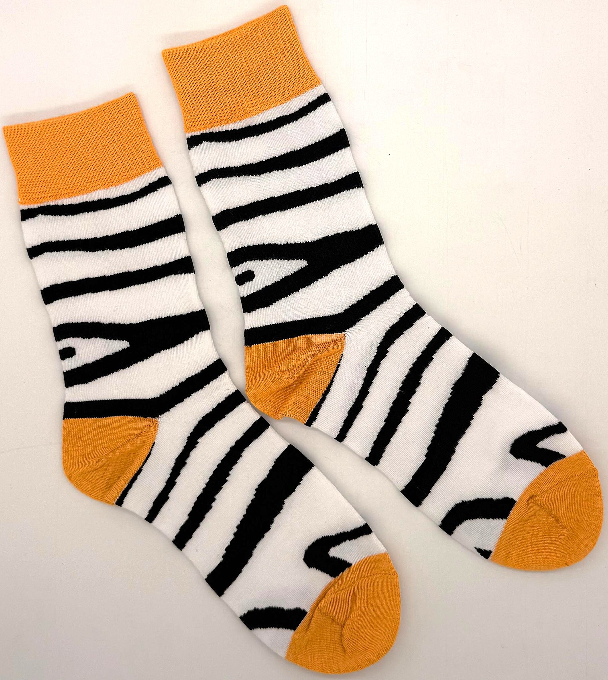 Pair of socks with black and white striped pattern and orange accents on a light gray background